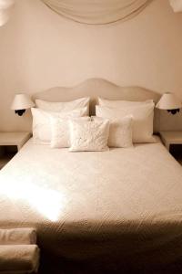 1 cama blanca con almohadas blancas y 2 lámparas en La Maison Kalogera, en Mykonos ciudad