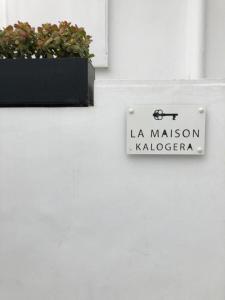 a sign on a white wall with a plant at La Maison Kalogera in Mikonos
