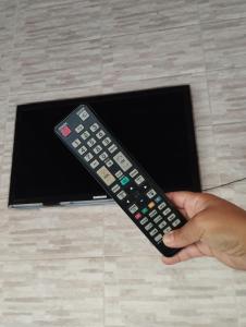a person holding a remote control in front of a tv at Aero Hostel in Londrina
