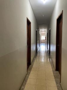 an empty hallway with doors and a tile floor at Hotel Boa Vista in Matipó