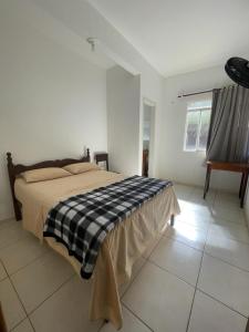 a bedroom with a bed with a black and white blanket at Hotel Boa Vista in Matipó