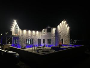 une maison éclairée la nuit avec des lumières bleues dans l'établissement Awel Y Trydan, à Llanon