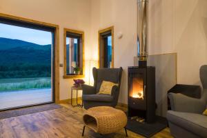 a living room with a fireplace and a view of the mountains at Luxury Cabins at Glenorchy Farm in Dalmally