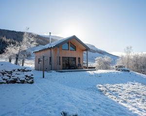 a cabin in the snow with a snow covered yard at Luxury Cabins at Glenorchy Farm in Dalmally
