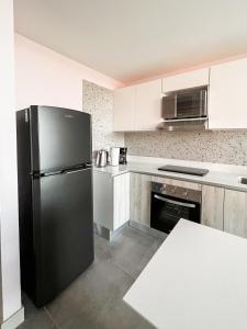 een keuken met een zwarte koelkast en witte kasten bij Chic & Stylish: Prime Apartment in La Sabana, Your Ideal Urban Oasis Awaits in Uruca