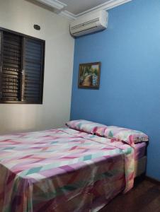 een slaapkamer met een bed en een blauwe muur bij Aero Hostel Londrina in Londrina