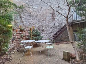 a table and chairs in front of a stone wall at Le Lapin dans la Cour in Tain-lʼHermitage