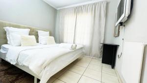 1 dormitorio con 1 cama con sábanas blancas y TV en Two Bedrooms at CASA MIA-Katode Street-in ANKAZIMIA HOUSE, en Roodepoort