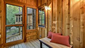 a log home porch with a bench and windows at The Poplar in Treehouse Grove at Norton Creek in Gatlinburg
