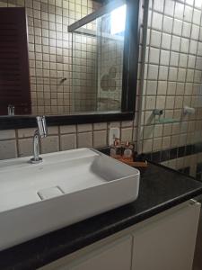 ein Badezimmer mit einem weißen Waschbecken und einem Spiegel in der Unterkunft Casa Mar - Vila Gameleira in São Miguel dos Milagres