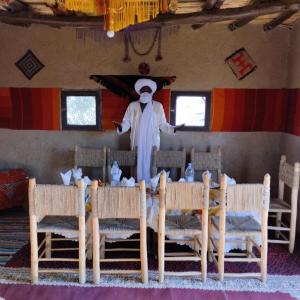 a man standing in a room with a table and chairs at Camp Familia Erg Chebbi in Merzouga