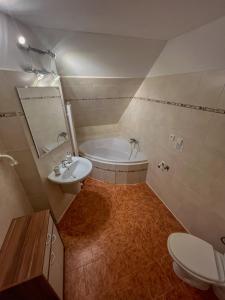 een badkamer met een bad, een wastafel en een toilet bij Penzion U Andresů in Zadov