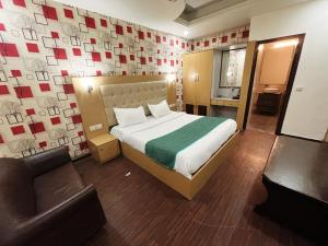 Hotel Diamond Airport في نيودلهي: غرفة نوم بسرير وكرسي وأريكة
