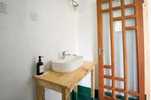 a bathroom with a white sink on a wooden table at Mkoani Homestay in Moshi