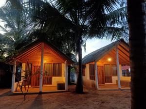 een klein huis met een palmboom ernaast bij Sand Dune Beach Resort & Surf Camp in Arugam Bay