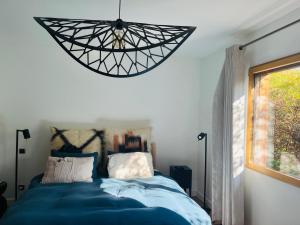 a bedroom with a blue bed and a chandelier at Villa Marie in Sévrier