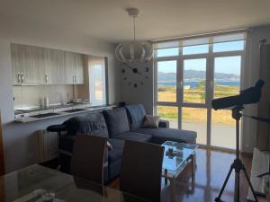 a living room with a couch and a table and a clock at APARTAMENTO CON EXCELENTES VISTAS AL MAR EN LA PLAYA DE CARNOTA in Caldebarcos