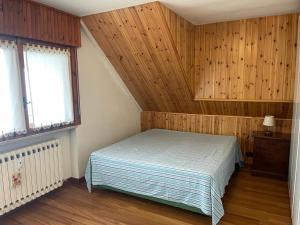 a bedroom with a bed and wooden walls and windows at Accogliente Appartamento Prato Nevoso in Prato Nevoso