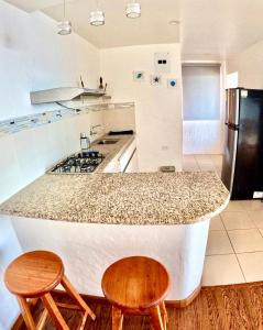 a kitchen with a counter with two chairs and a refrigerator at Suite Cielo, Discover the magic of Galapagos in Puerto Baquerizo Moreno