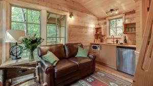 salon ze skórzaną kanapą w kuchni w obiekcie The Dogwood in Treehouse Grove at Norton Creek w mieście Gatlinburg