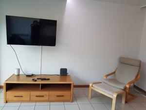a room with a chair and a tv on a wall at Studio dans résidence de standing avec parking et sa terrasse vue mer in Bidart