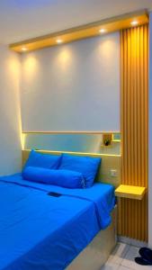 uma cama com almofadas azuis num quarto em DND Room Aero em Teko