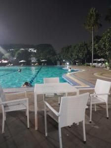 uma mesa e cadeiras ao lado de uma piscina à noite em DND Room Aero em Teko