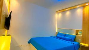 um quarto com uma cama azul e uma televisão em DND Room Aero em Teko
