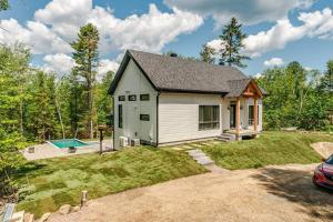 a small white house with a pool in the yard at Le Montagnard Spa Sauna Piscine Privés in Brownsburg