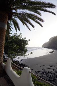 a hammock on a beach with a palm tree at Playa Chica Beachfront Apartment in Santa Cruz de Tenerife