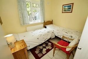 een kleine slaapkamer met een bed en een stoel bij Sea view bungalow in The Mumbles
