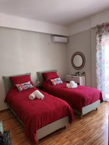 2 Betten in einem Schlafzimmer mit roter Bettwäsche und einem Spiegel in der Unterkunft Στούντιο Διπλα στην Ακρόπολη in Athen