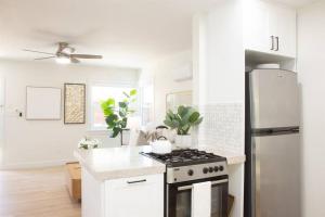 uma cozinha branca com um fogão e um frigorífico em Live the Beach Life in a Quaint Shell Cottage em Del Mar