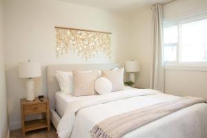 a bedroom with a large bed with white sheets and pillows at Live the Beach Life in a Quaint Shell Cottage in Del Mar