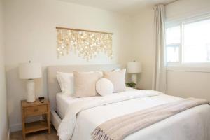 a bedroom with a large bed with white sheets and pillows at Live the Beach Life in a Quaint Shell Cottage in Del Mar +28 photos