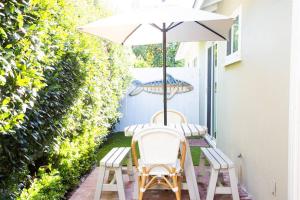 two chairs and an umbrella on a patio at Live the Beach Life in a Quaint Shell Cottage in Del Mar