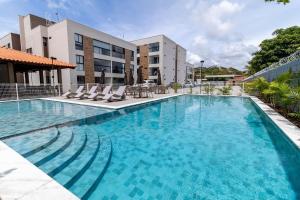 ein großer Pool mit Stühlen und ein Gebäude in der Unterkunft Elegância Tropical San Martin - Destino BSM 303 C in Barra de São Miguel