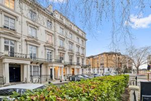 un gran edificio blanco con coches estacionados frente a él en Cosy 2BR Retreat near Paddington Station, en Londres