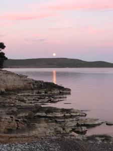 a sunset over the water with the moon in the sky at Gajeta Residence Božava in Božava