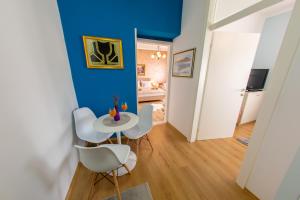 a dining room with blue walls and white chairs at Apartman Hersek Mostar in Mostar