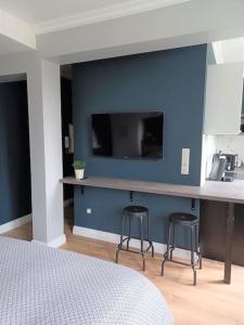 Au cœur de la Grand Place في أراس: غرفة نوم بحائط ازرق مع تلفزيون ومقعدين للبار