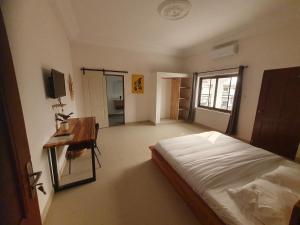 a bedroom with a bed and a desk in it at Cocoon Guest House in Cotonou