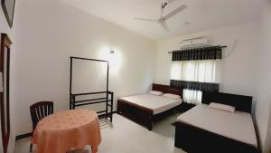 Cette chambre comprend 2 lits, une table et un miroir. dans l'établissement Hotel Sanhida Polonnaruwa, à Polonnâruvâ