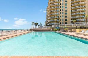 a large swimming pool next to a beach with a building at Oceanside Duo - Double Room, Water Views, Pool & Beach Access, Free Parking in Daytona Beach