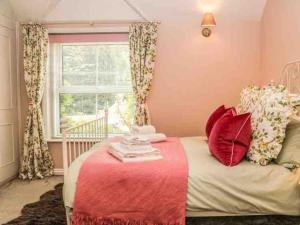 a bedroom with a bed with red pillows and a window at Charming Country Cottage in Selborne