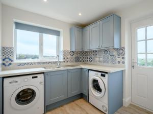 a kitchen with blue cabinets and a washer and dryer at 3 Bed in Worth Matravers 80578 in Worth Matravers
