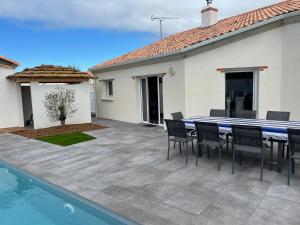 a patio with a table and chairs next to a swimming pool at MAISON NOTRE DAME DE MONTS in Notre-Dame-de-Monts