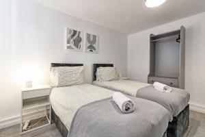 - 2 lits dans une chambre aux murs blancs dans l'établissement Newly Refurbished 3BR House Basildon, Garden, Netflix & Trisport Table, à Nevendon