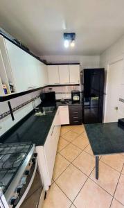 cocina con armarios blancos y nevera negra en Casa en condominio jardines del norte Antofagasta., en Antofagasta