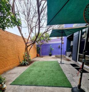 une pelouse verte devant un bâtiment avec un parasol dans l'établissement Casa en condominio jardines del norte Antofagasta., à Antofagasta